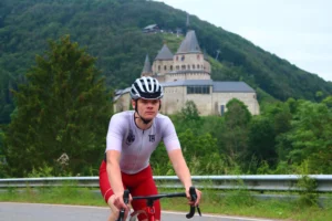 Wesley Klimmend in luxemburg met een kasteel op de achtergrond in custom wielerkleding