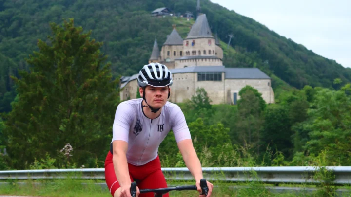 Wesley Klimmend in luxemburg met een kasteel op de achtergrond in custom wielerkleding